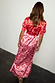 Pink and Red May Dress with iconic sun and shell motifs, short puff sleeves and a shirred back detail on a model.