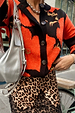 Black Poppy Cardigan with a bold poppy print and button-up front, styled with a leopard print skirt and silver bag.