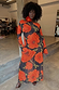 Black Poppy Aria Mesh Dress with large red poppies on sheer black fabric, worn by a model with a floral neck accessory.