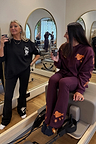 Burgundy cotton wide leg pants with coral embroidery and a matching hoodie for a gym co-ord in a pilates studio.