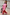 Thumbnail for Pink Bandana Copenhagen Jumper with an iconic red print and necktie, styled for a vacation with a suitcase.