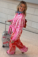 Pink Bandana Copenhagen Jumper with an iconic red print and necktie, styled for a vacation with a suitcase.