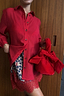 Thumbnail for Red Velvet Bow Bag in red velvet featuring a statement bow, styled with a red shirt and leopard print skirt.