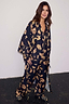 Deloris Satin Robe in black with iconic gold motifs, styled with matching pyjamas and slippers for a full nightwear set.