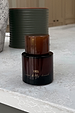 NFD Eau De Parfum 001 in a dark amber glass bottle with a tortoiseshell cap on a white marble surface.