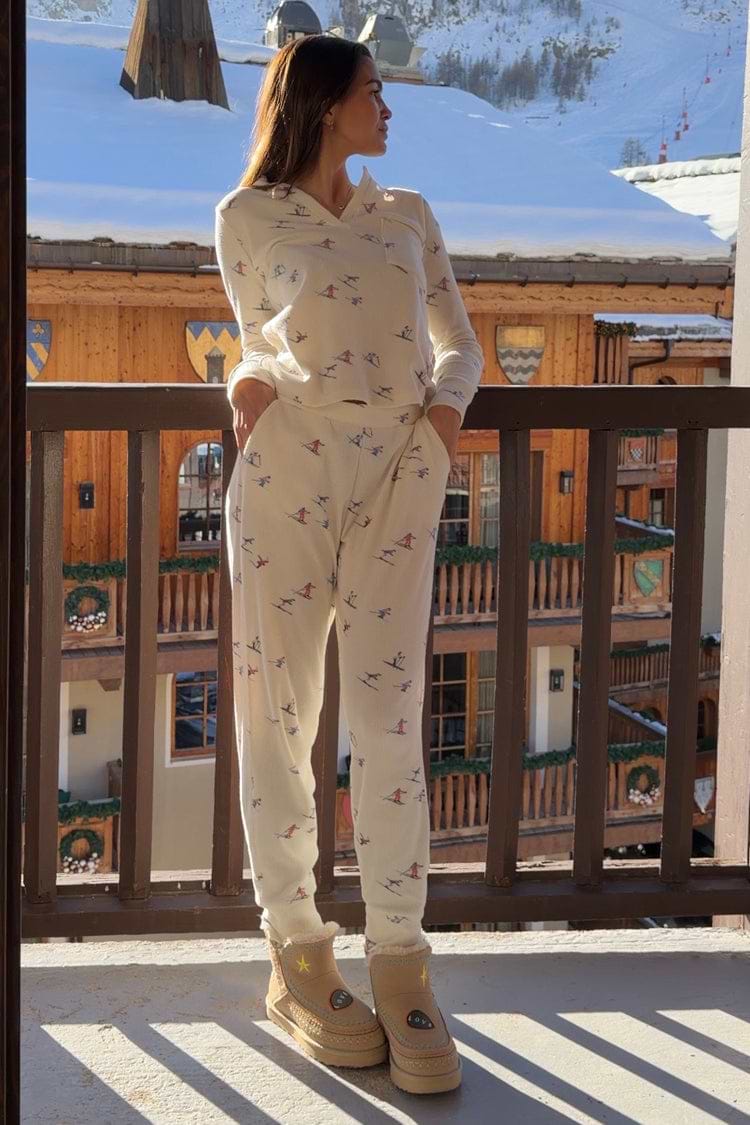 White Ski Waffle Pyjamas with a ski print, long-sleeved top and slim trousers, styled on a snowy balcony.
