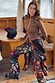 Night Garden Ski Suit featuring leopard and poppy prints, worn by a 5ft7” model in a UK size 10/ US 6 in a wooden chalet.