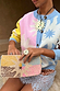 Soleil Bag featuring hand-embellished beads in cream and pastel sun patterns, styled as a clutch.