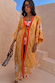 Yellow Sun Kimono in Soleil print with orange trim, tie front and wide sleeves, styled for a vacation with a beaded bag.