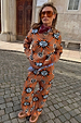 Tan Sun knit co-ord with sun and swirl motifs, styled with a bandana and sunglasses on a cobbled street.