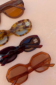 Red tortoise acetate sunglasses featuring statement wiggle arms and dark lenses with gold logo detailing.