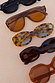 Yellow Tort Wiggle Arm Sunglasses with light blue lenses and distinctive wavy arms, shown in a row of NFD eyewear.