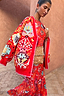 Thumbnail for Tomato Tapestry Martha Cardigan with pink blanket stitch detailing layered over a matching red print dress.