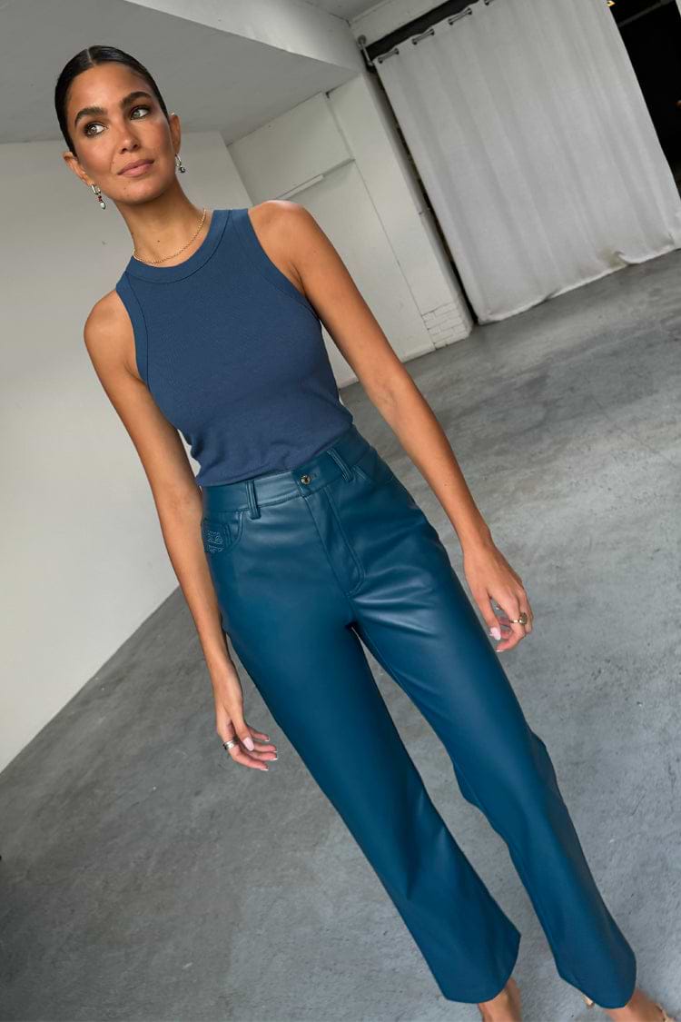 Teal straight leg vegan leather trousers and a navy ribbed tank top worn by a model.