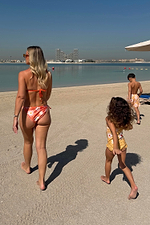 Orange Sun Tie Side Bikini Brief with soleil motifs, styled on a beach with matching family swimwear.