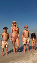Orange Sun Tie Side Bikini Brief with in-house soleil print, worn on a beach with family in matching swimwear.