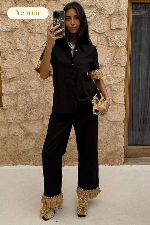 Black Raffia Marra Trousers featuring tan raffia fringe at the hem, styled with a matching shirt and accessories.