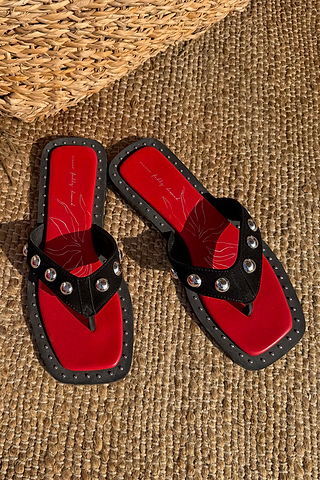 Black Leather Stud Sandals with silver studs and a red square-toe footbed on a woven mat.