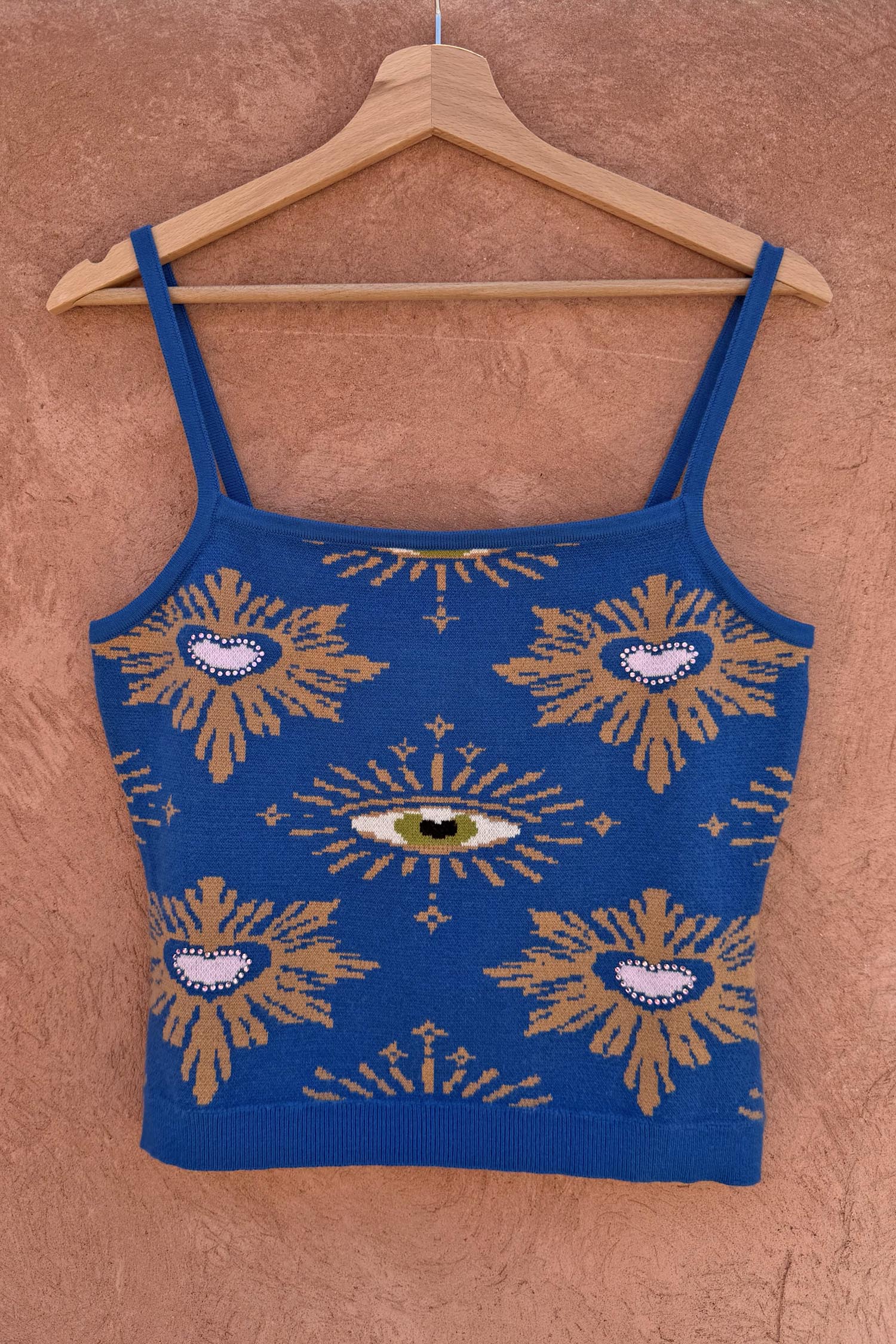 Blue Eye Knitted Cami Top with heart and eye motifs and a square neckline, hanging on a wooden hanger.