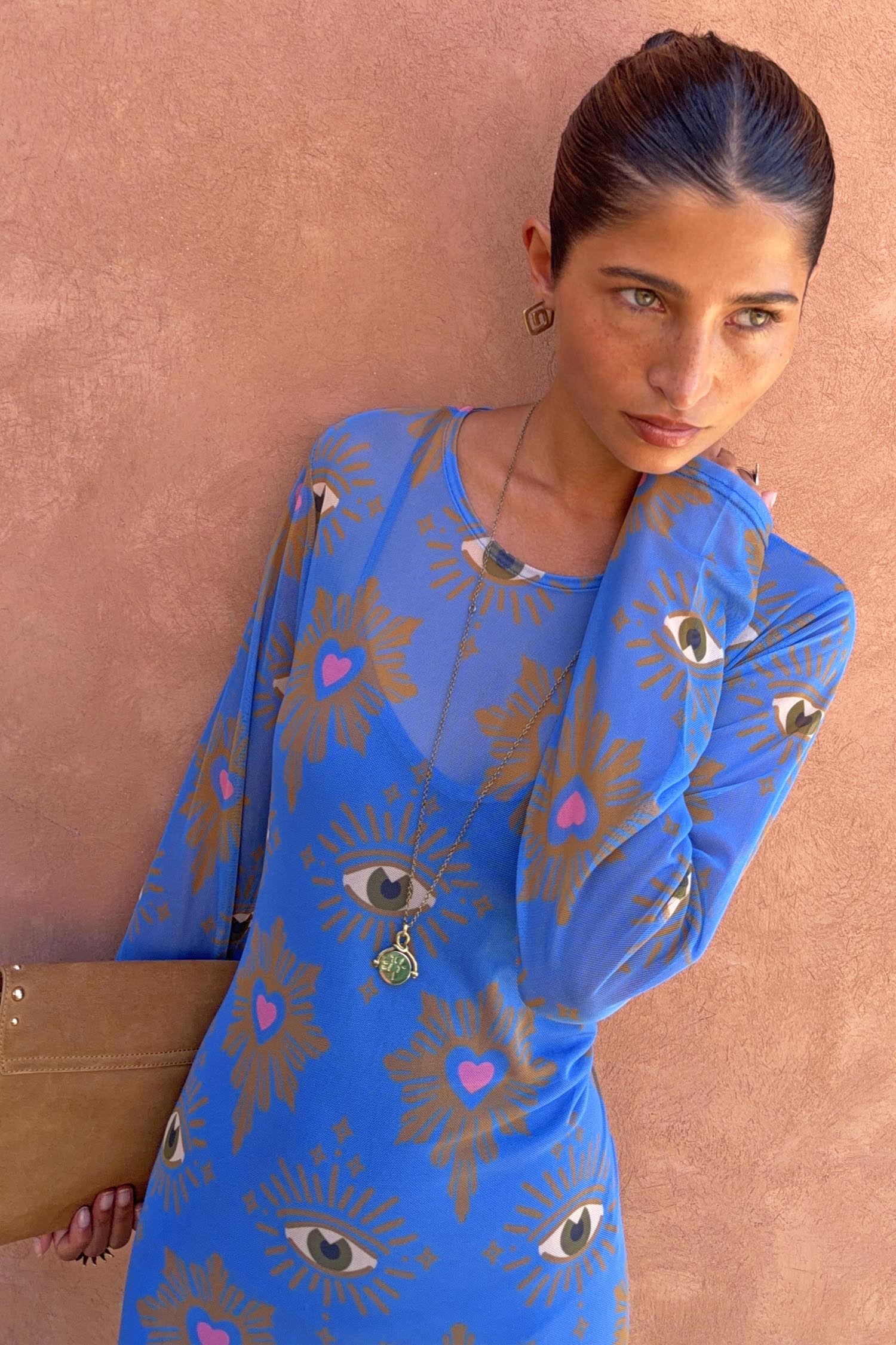 Blue Eye Mesh Dress with eye and heart motifs, long sleeves and a fitted silhouette against a textured wall.
