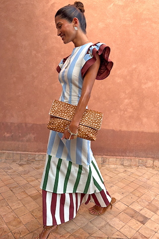 Blue Stripe Alena Midi Dress featuring tiered striped panels and burgundy ruffle sleeves, paired with a spotted clutch.