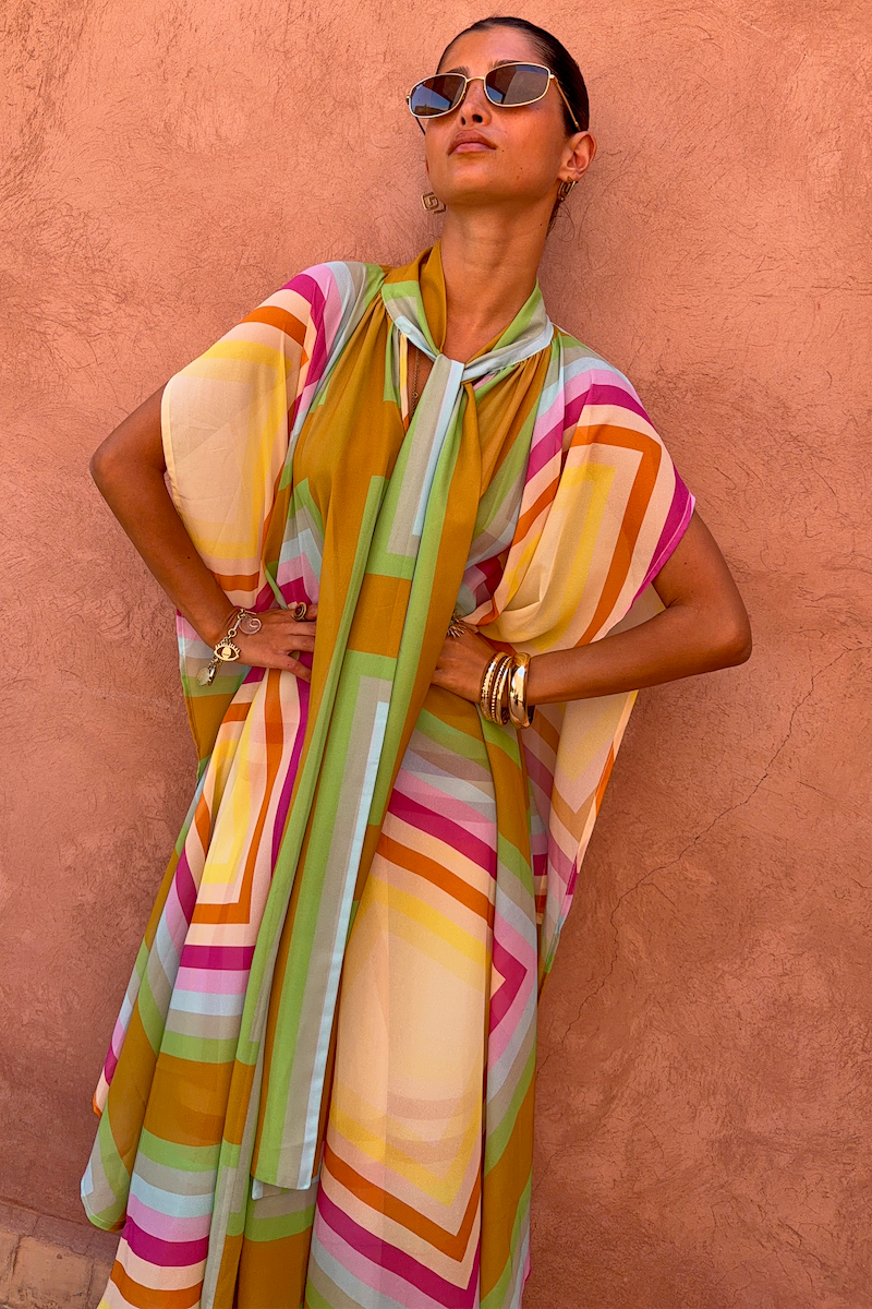 Bright Geo Stevie Maxi Dress with a colourful geometric stripe print and scarf-tie neckline on a model.
