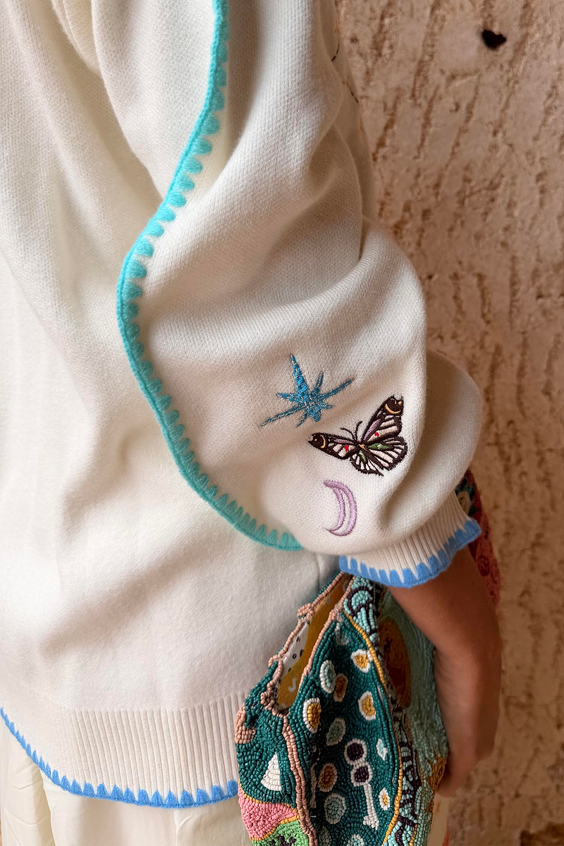 Cream Celestial Martha Cardigan sleeve featuring embroidered cosmic motifs and blue blanket stitch trim.