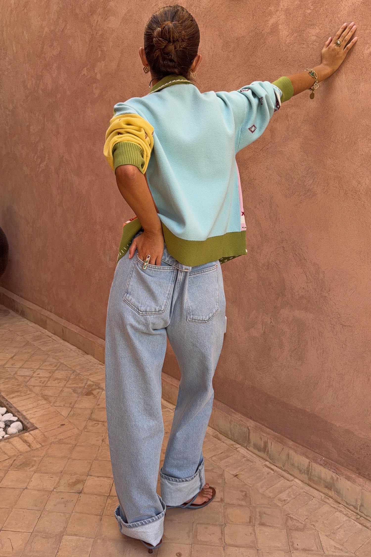 Geometric Palm Cardigan with blue and green colour-blocking and palm motifs, styled with light wash jeans.