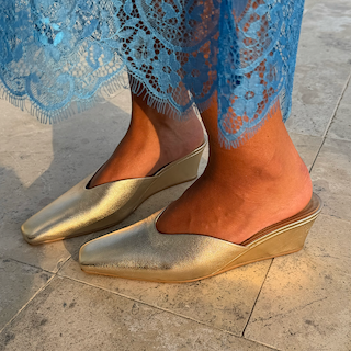 Metallic Gold Wedge Mule heels with a pointed toe and sculpted heel, styled with a blue lace dress.