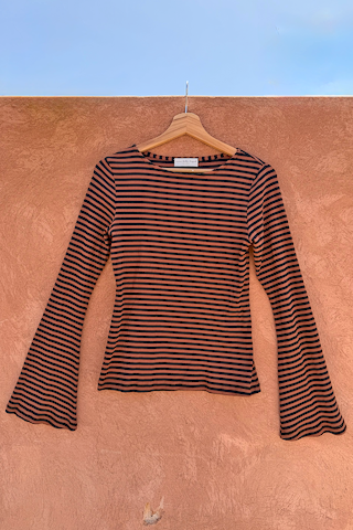 Ribbed Chocolate Stripe Top with flared bell sleeves hanging on a wooden hanger against a terracotta wall.