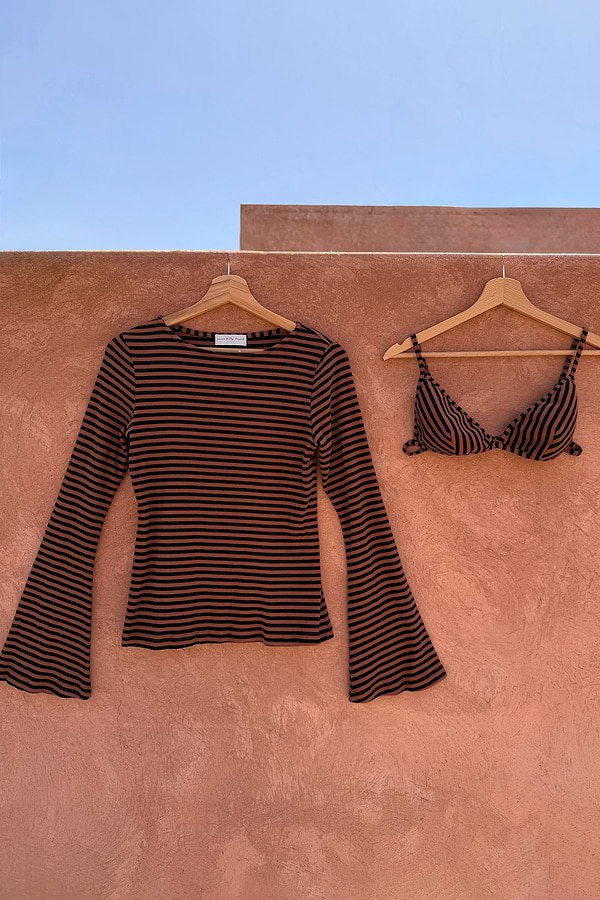 Ribbed chocolate stripe top with flared sleeves and matching bra set hanging against a terracotta wall.