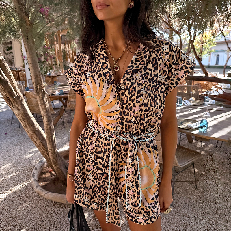 Leopard and soleil print playsuit featuring turquoise trim, a button-through front and adjustable tie waist on a model.