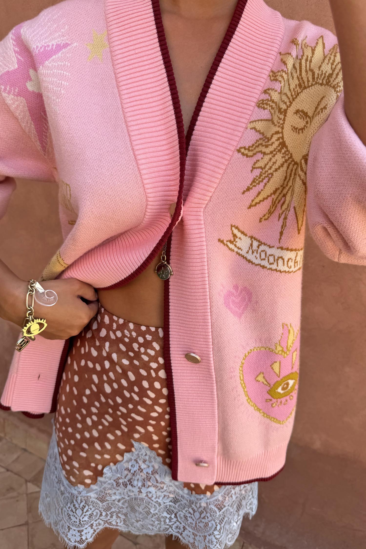 Pink Mystical Cardigan with sun and moon jacquard motifs, burgundy trims and a transeasonal soft knit finish.