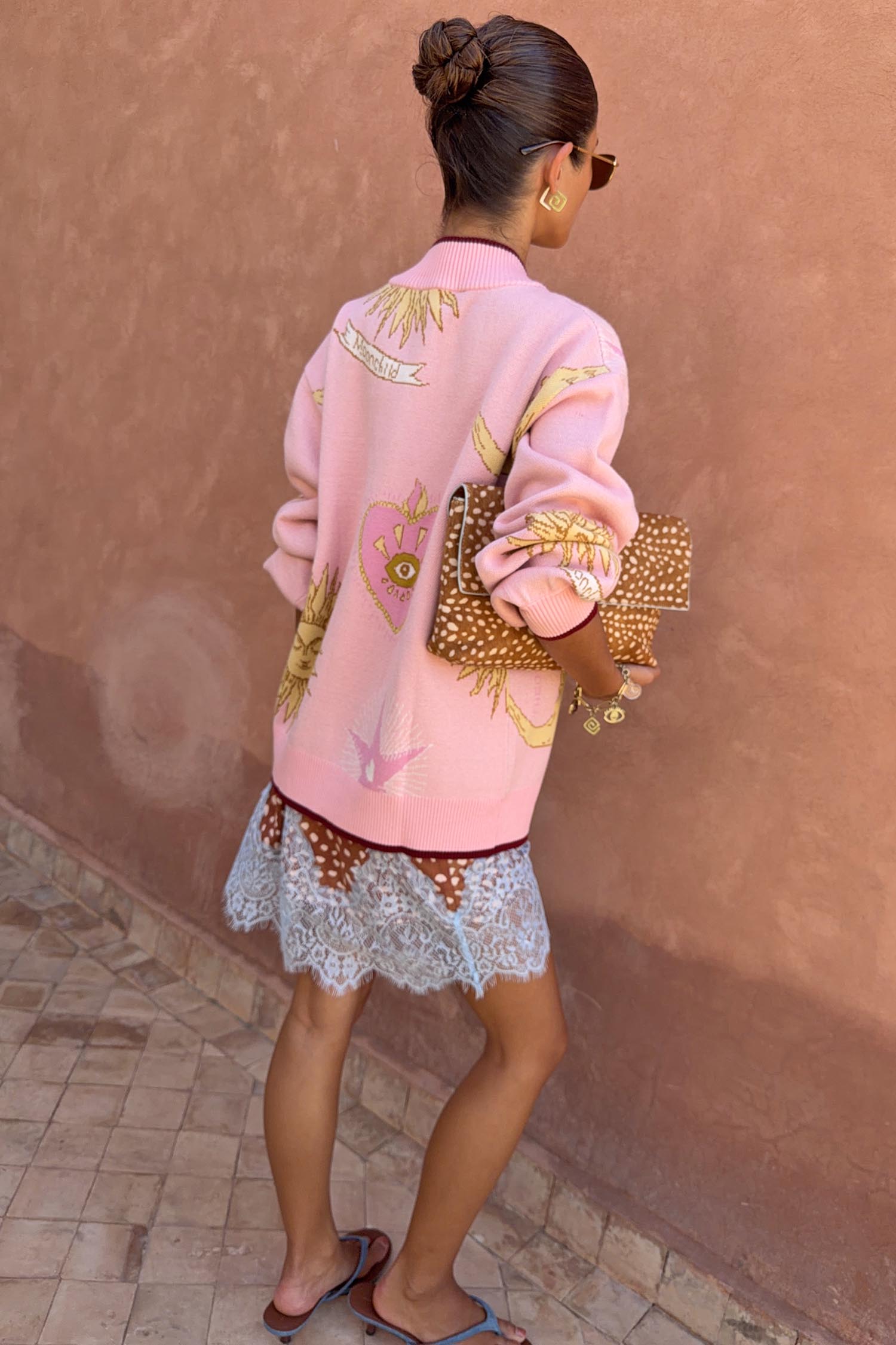 Pink Mystical Cardigan with sun and moon jacquard motifs and burgundy trims, shown from the back on a model.