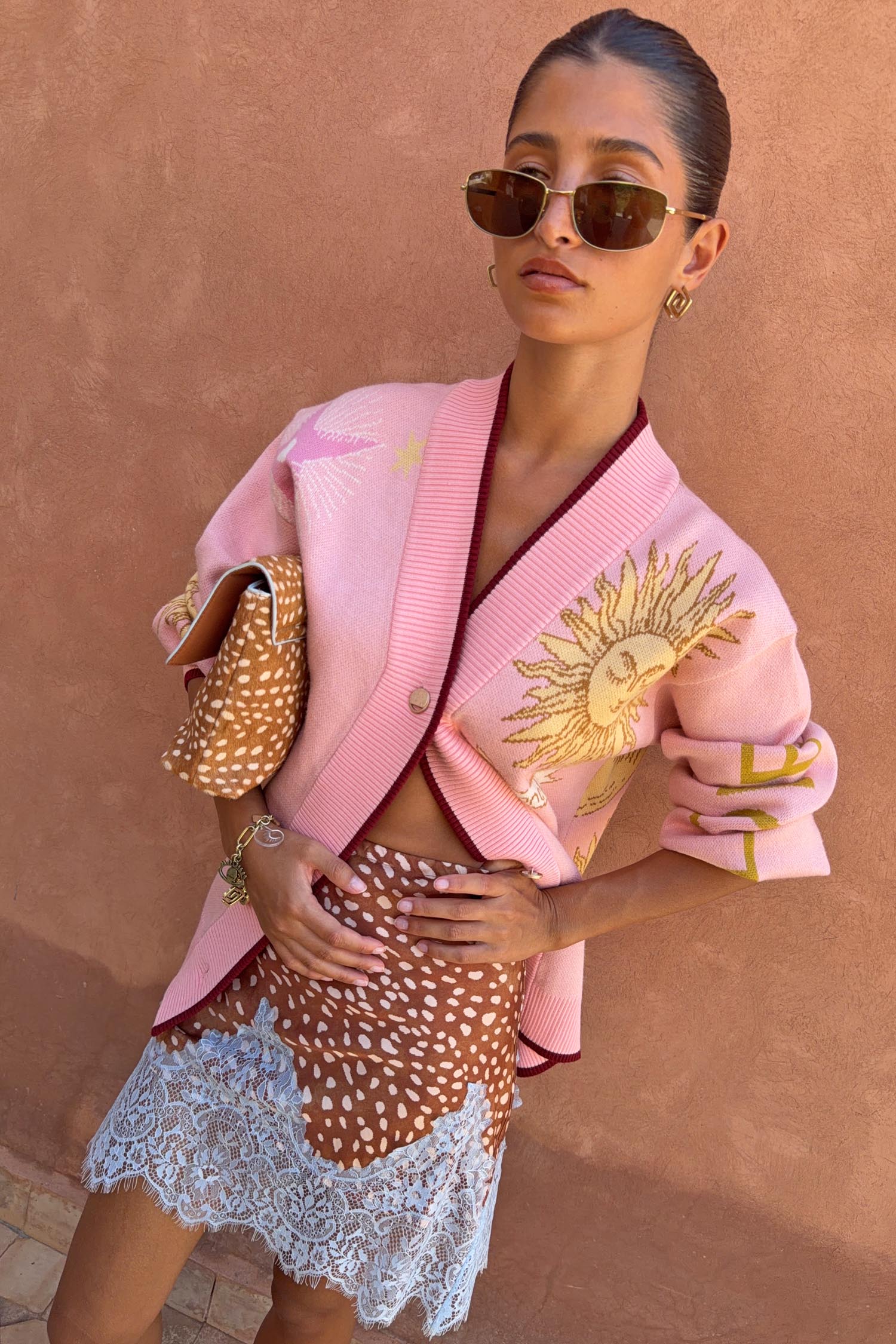 Pink Mystical Cardigan in a soft knit with a sun jacquard motif and burgundy trims, paired with a patterned lace skirt.