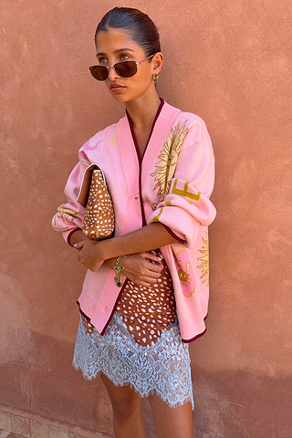 Pink Mystical Cardigan with jacquard sun and moon motifs and burgundy trims, styled with a lace-trimmed dress.