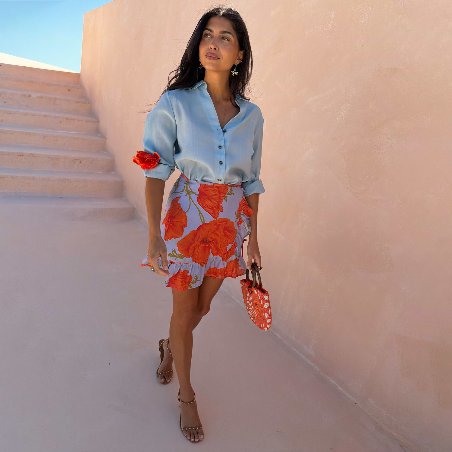 Blue Poppy Mini Jaspre wrap skirt with a bold floral print and frill hem, styled with a light blue shirt.