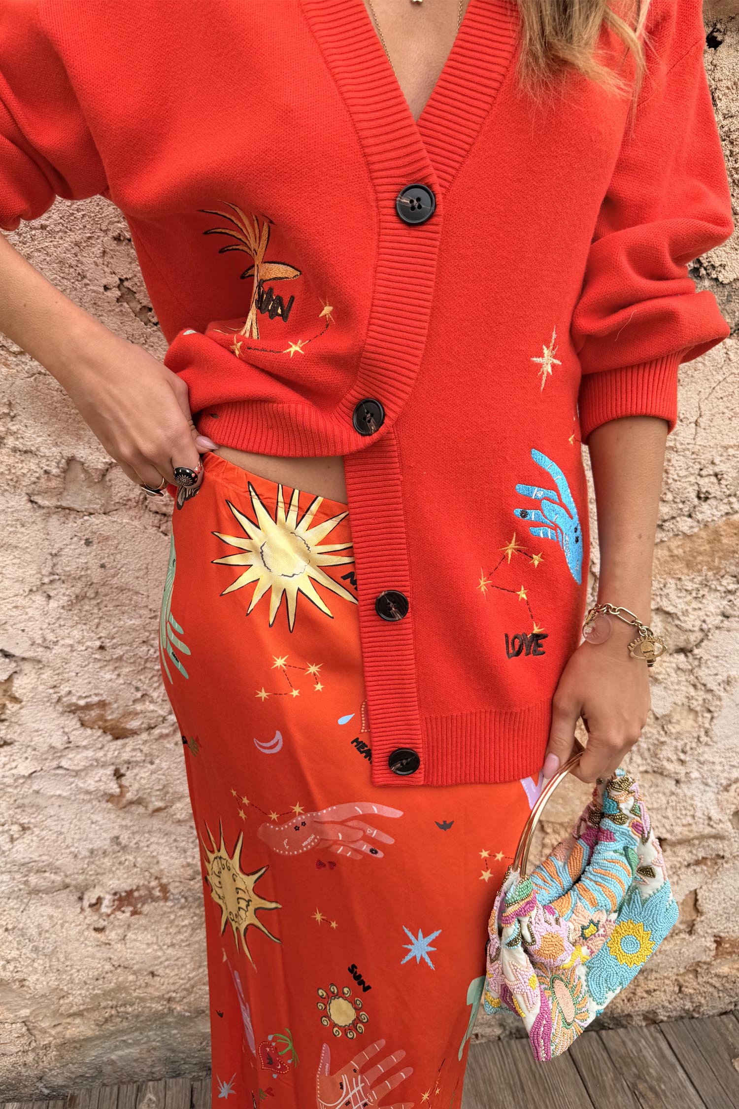 Red Celestial Dorris Skirt in satin with hand-painted sun motifs, styled with a matching red cardigan.