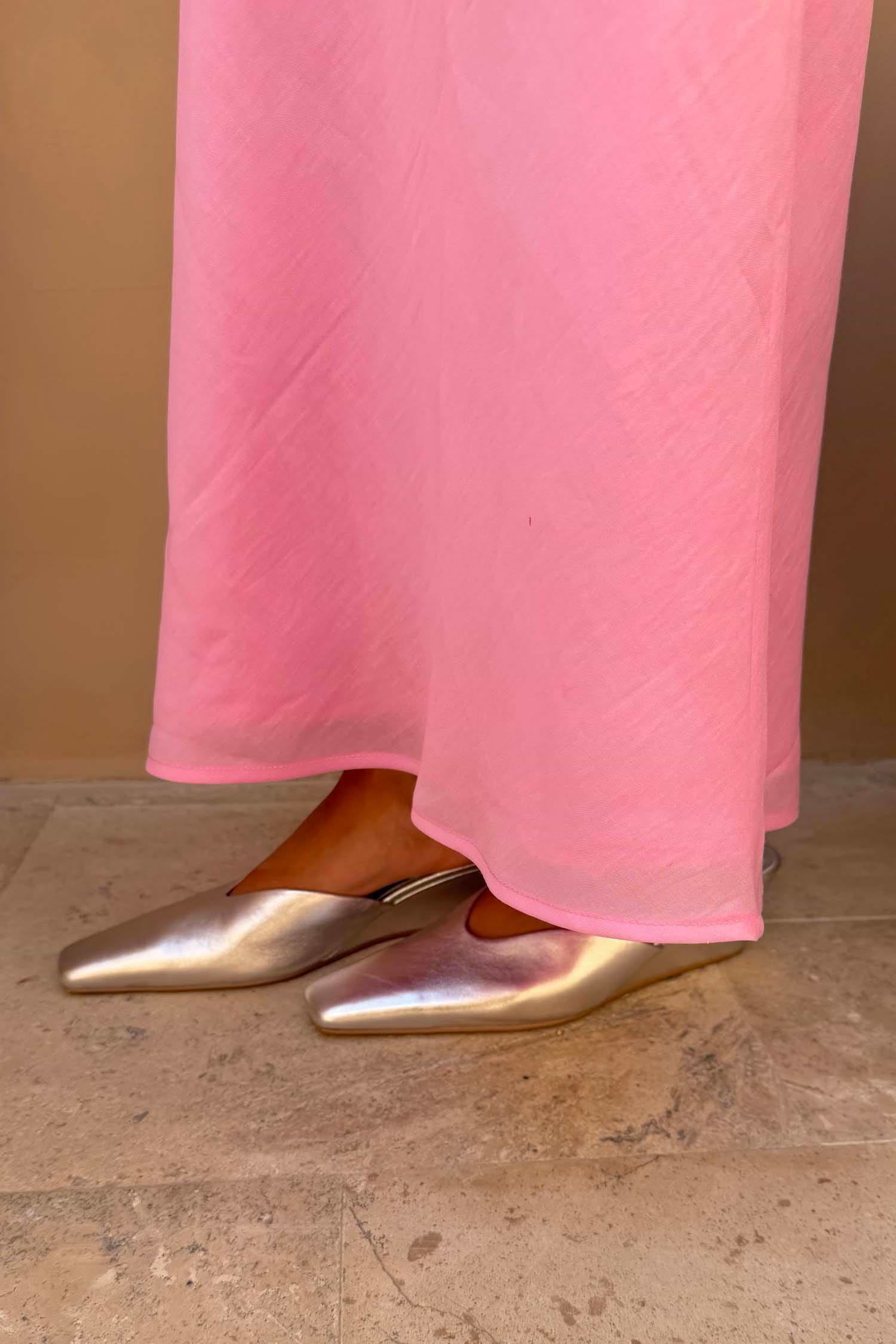 Silver Wedge Mule in metallic leather with a pointed toe and sculpted wedge heel, worn with a pink skirt.