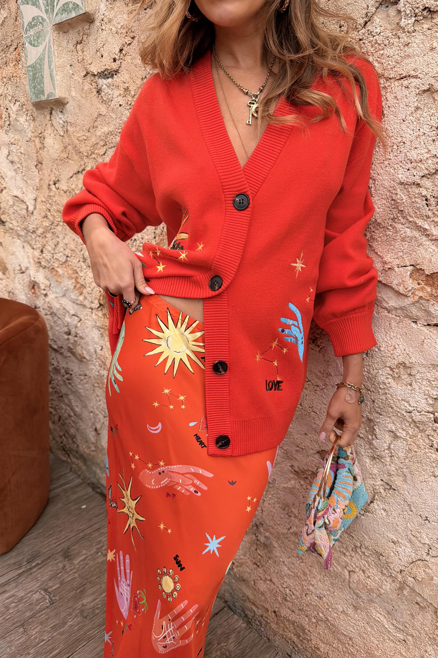 Red Celestial Cardigan featuring embroidered sun and star motifs, styled with a matching printed co-ord skirt.