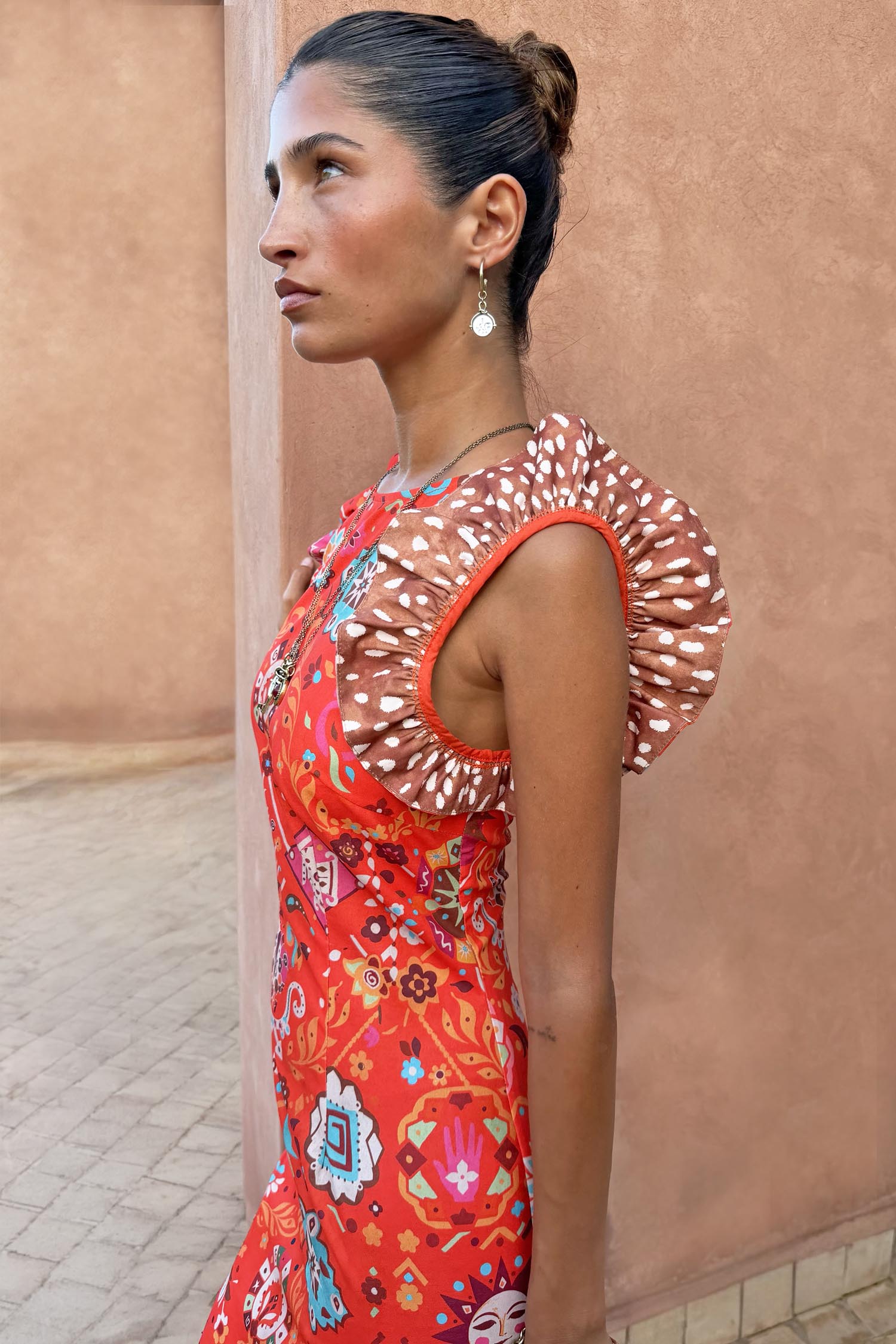 Tomato Tapestry Frida Dress in red featuring sun motifs and contrasting spot print ruffle sleeves.