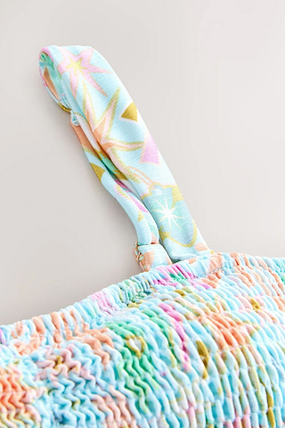 Blue Dreamer Shirred Bandeau Top detail featuring light blue shirred fabric and an adjustable strap with sun motifs.