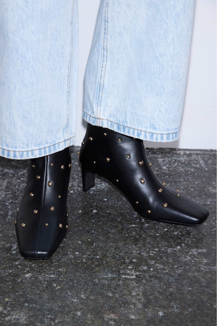 Black Leather Boots with Gold Studs, square toe and block heel, styled with light-wash denim jeans.