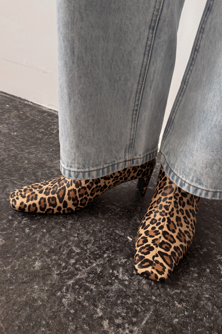 Leopard print boots with a square toe and thin block heel, paired with light blue denim jeans.