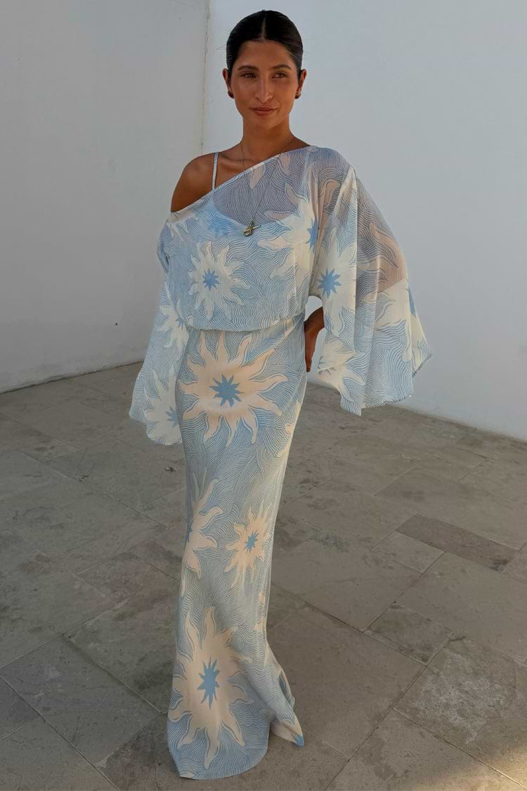 Blue Soleil Anais Dress with a Mediterranean sun print, draped sheer off-shoulder top, and sleek bias-cut skirt.