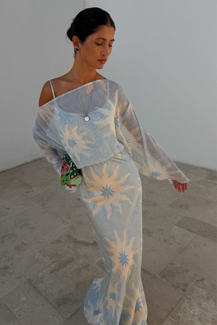 Blue Soleil Anais Dress with a Mediterranean sun print, sheer off-the-shoulder top and satin-esque skirt.