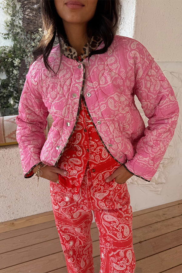 Reversible pink bandana quilted jacket with leopard trim and popper fastenings, styled with matching red trousers.