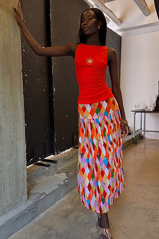 Pleated Cirque Beatrice Skirt with a colourful geometric diamond pattern and circus motifs on a model.