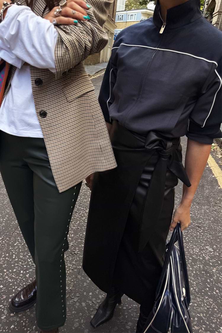 Iconic Black Vegan Leather Jaspre Wrap Skirt with a tulip shaped tie, styled for a London street look.