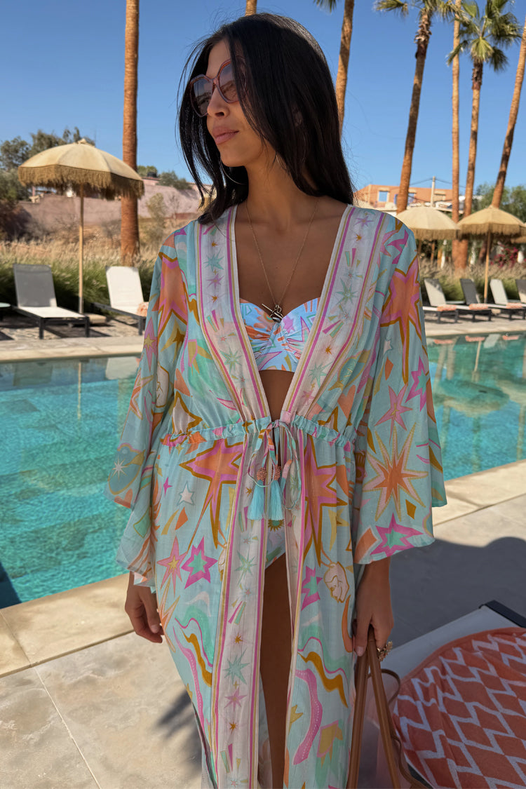 Blue Dreamer Maxi Kimono in light blue with star and heart motifs, styled poolside with a tie waist and tassels.